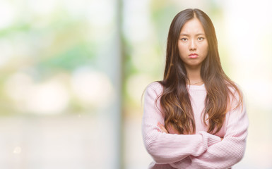 Young asian woman over isolated background skeptic and nervous, disapproving expression on face with crossed arms. Negative person.