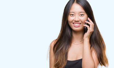 Young asian woman speaking on the phone over isolated background with a happy face standing and smiling with a confident smile showing teeth