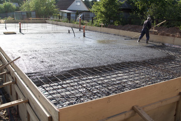 worker leveling fresh concrete slab with a special working tool