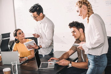 group of multiethnic business colleagues having meeting with laptops and digital tablet at modern office
