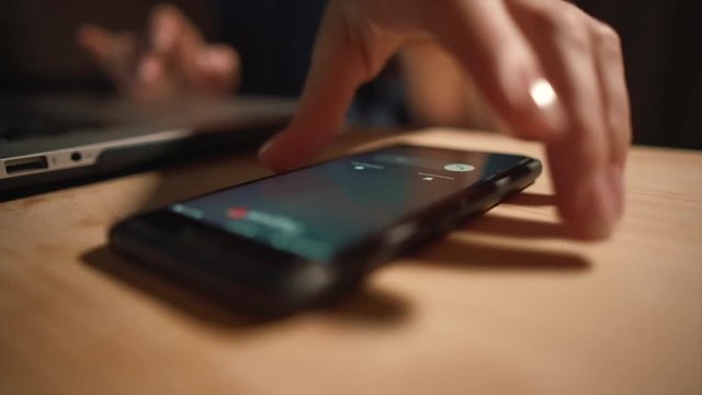 Someone is calling on the phone. The girl picks up the phone from the table. Wood table