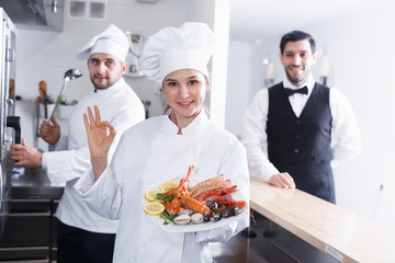 Woman chef approving dish in fish restaurant