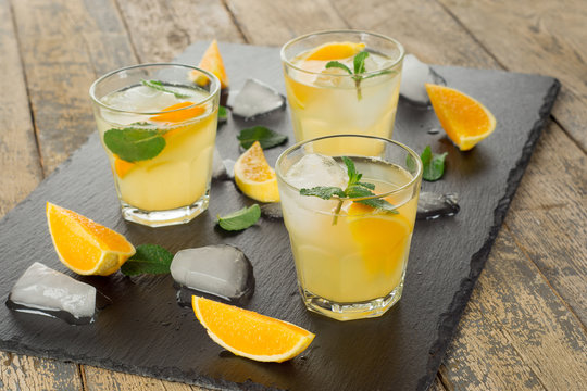 Cocktail. Orange juice with mint and ice on rustic wooden table