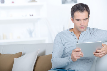 middle-aged man using digital tablet on sofa