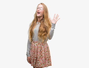 Blonde teenager woman wearing flowers skirt showing and pointing up with fingers number five while smiling confident and happy.