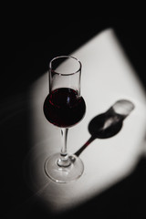 A tulip glass of red port wine in harsh sunlight with deep shadows and bright highlights.