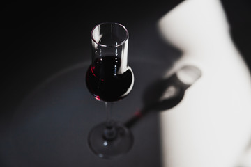 A tulip glass of red port wine in harsh sunlight with deep shadows and bright highlights.