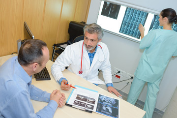 male doctor showing xray to patient nurse in the background