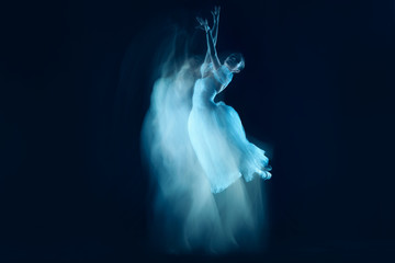 The photo as art - a sensual and emotional dance of beautiful ballerina through the veil on a dark background. A stroboscopic image of the one model