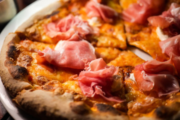 Delicious, cheesy and freshly baked Italian Prosciutto di Parma pizza or pizza with Tomato, mozzarella, prosciutto ham and Parmesan cheese. Selective focus. Close up.