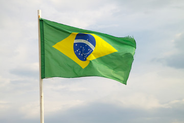 Brazilian flag on a blue sky with clouds background