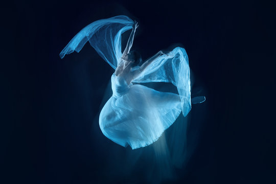 Fototapeta The photo as art - a sensual and emotional dance of beautiful ballerina through the veil on a dark background. A stroboscopic image of the one model