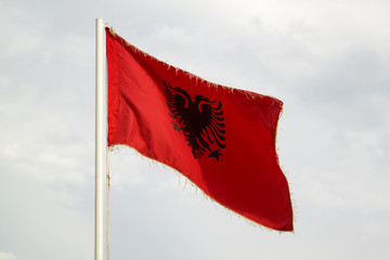 Albanian flag on a blue sky with clouds background