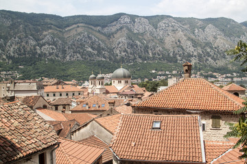 Fototapeta premium view of medieval tiled roofs of stone houses with windows and wooden shutters in the old town of Kotor, Montenegro