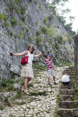 Naklejka premium family value. happy mother with her son and daughter climbs the mountain up the steps to see the stunning view from the top of the medieval town of Kotor, Montenegro