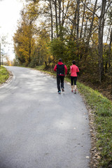 Fototapeta premium Young couple running on the sunny day in the autumn forest of the Bavarian National Park, Bavaria, Germany