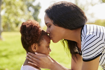 Close Up Of Mother Kissing Daughter In Park