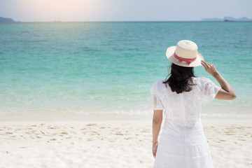 Fototapeta na wymiar a beautiful carefree Woman relaxing at the beach enjoying her sun dress freedom wear.
