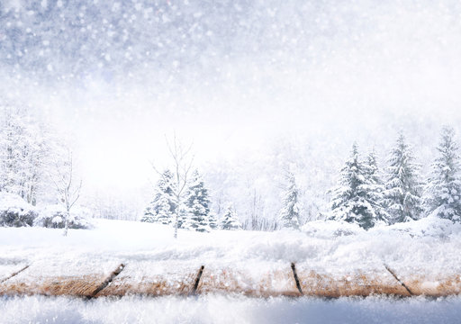 Winter christmas scenic background with copy space. Wooden flooring strewn with snow in forest and landscape with fir-trees covered with snow on nature.