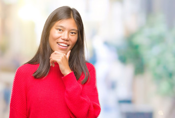 Young asian woman wearing winter sweater over isolated background looking confident at the camera with smile with crossed arms and hand raised on chin. Thinking positive.