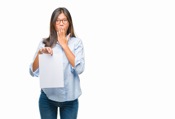 Young asian woman over isolated background holding blank paper cover mouth with hand shocked with shame for mistake, expression of fear, scared in silence, secret concept