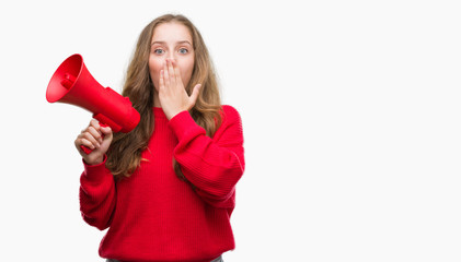 Young blonde woman holding red megaphone cover mouth with hand shocked with shame for mistake, expression of fear, scared in silence, secret concept