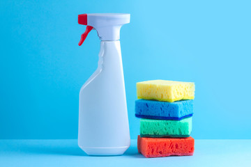 Spray for cleaning houses and sponges for washing dishes on a blue background. Cleaning products