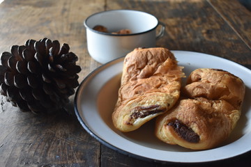 Plato antiguo con bollos, taza con galletas y piña de pino de adorno