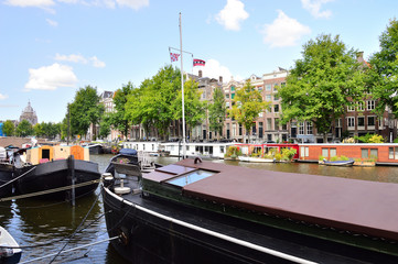 Barki na kanale w Amsterdamie przy pirsie.