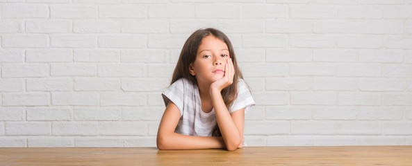 Young hispanic kid sitting on the table at home thinking looking tired and bored with depression...