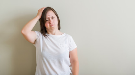 Down syndrome woman standing over wall confuse and wonder about question. Uncertain with doubt, thinking with hand on head. Pensive concept.