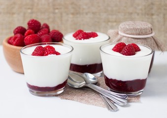 Three glass cups of fresh white yogurt with raspberries