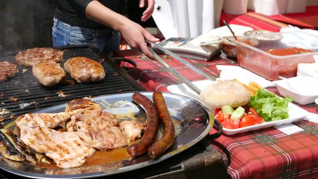 Cooking meat dishes on a big grill table on street food festival - Balkan cuisine