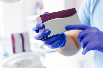 Male dentist holding small madicine box