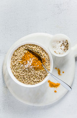 whole-grain rice with turmeric in a bowl on a white marble board. ingredients of a vegan healthy kitchen