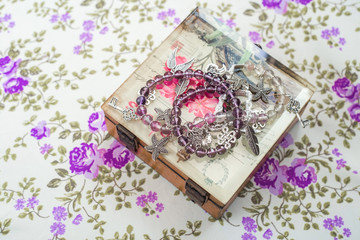 silver bracelet with natural stones, shaped beads and crystals on a purple textile background,...