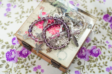 Fototapeta na wymiar silver bracelet with natural stones, shaped beads and crystals on a purple textile background