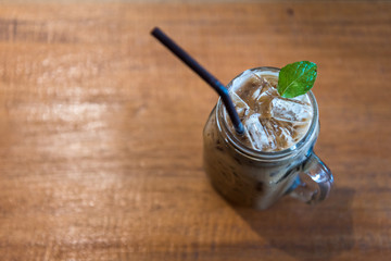 Ice coffee in glass on wooden table, top view
