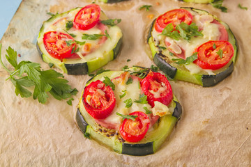 Zucchini small round pizza with pepperoni and tomatoes.