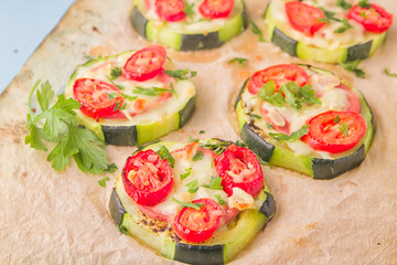 Zucchini small round pizza with pepperoni and tomatoes.