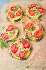 Zucchini small round pizza with pepperoni and tomatoes.