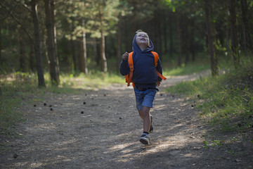 A happy little boy  runs along a forest path