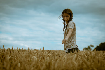 Young blond girl with wet hair and tshirt playing in a cornfield