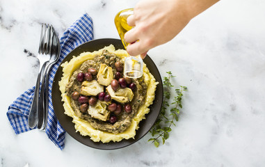 two plates with mashed potatoes, baba ganush, artichokes in oil and olives on the table. healthy vegan cuisine