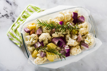 autumn vegetables in a glass baking tray: cauliflower, potatoes and red onions. healthy baked food in the oven.