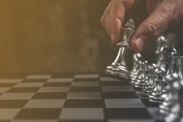 Chess game, chess player makes a move the silver king one step forward. Chess pieces on the board....