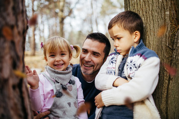 Happy young father with his son and doughter enjoying in autumn park.
