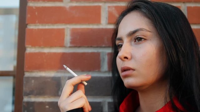 A young woman smokes a cigarette.