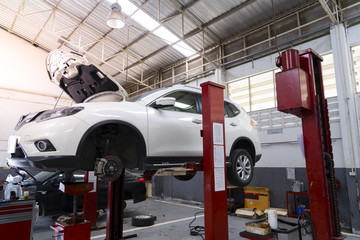 A car is lifted on a bridge in a car garage