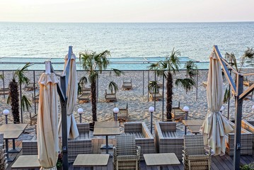 sunbeds and furniture with umbrellas on the beach with palm trees in the sand against the sky and...